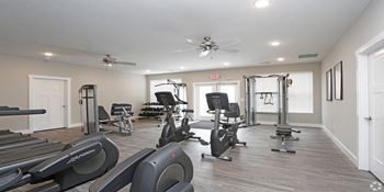 a gym with cardio equipment and a ceiling fan